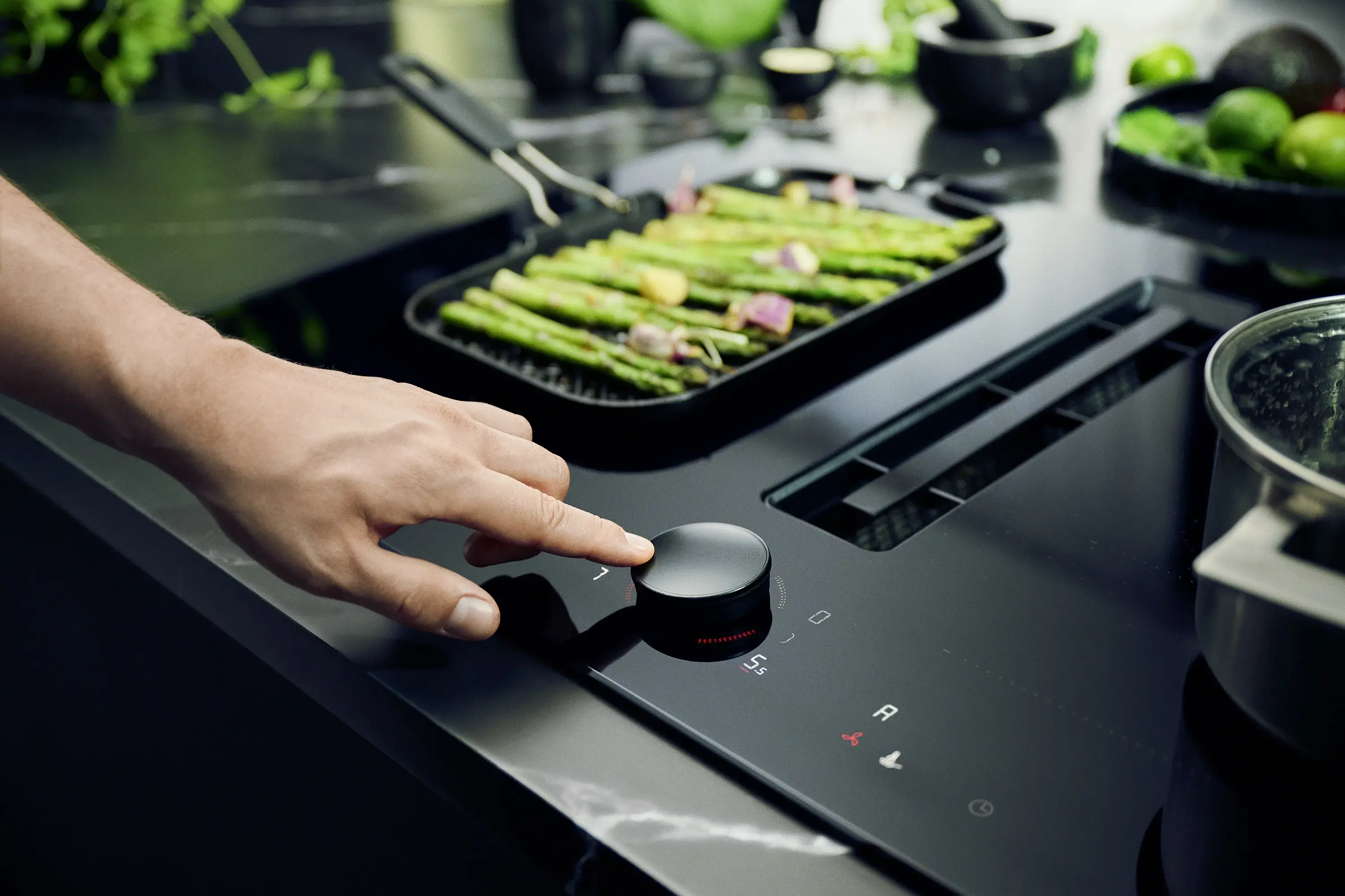 Hand bedient Twist Pad Flex Drehknebel an Kochfeld mit grünem Spargel in Pfanne